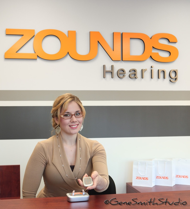 Attractive saleswoman offers hearing aid equipment.