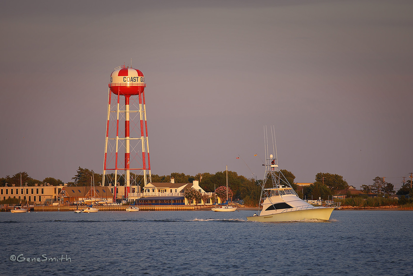 Cape May New Jersey's Corinthian Yacht Club at late afternoon with pastel green Ocean Yacht cruising home to it's berth. The Corinthian Yacht Club is adjacent to the Cape May Coast Guard Station and the Station, Cape May's large water tower recently refinished is painted bright red and white to add visibility to mariners at sea.