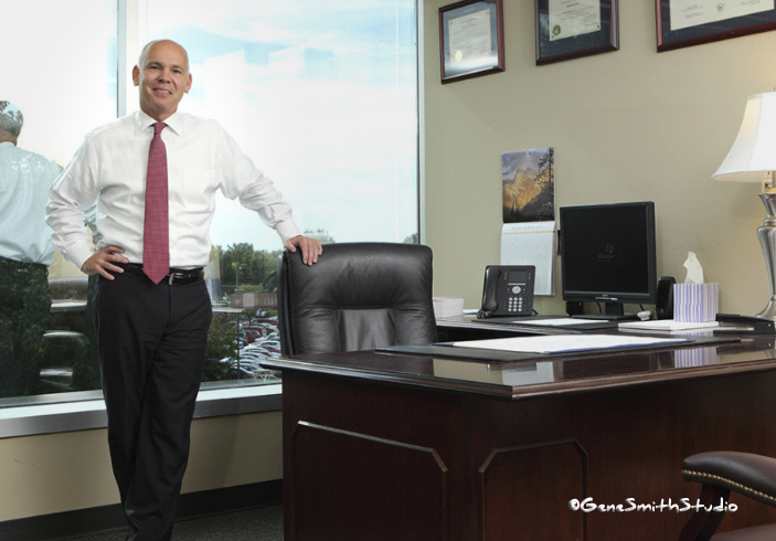Location Portrait of executive standing next to window at desk