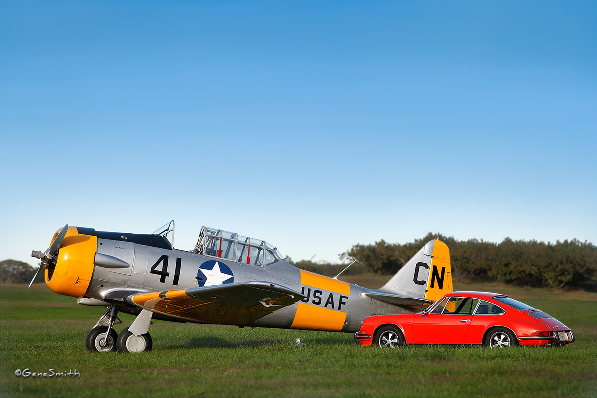 Vintage airplane trainer and 1969 PORSCHE 911S parked in airstrip field