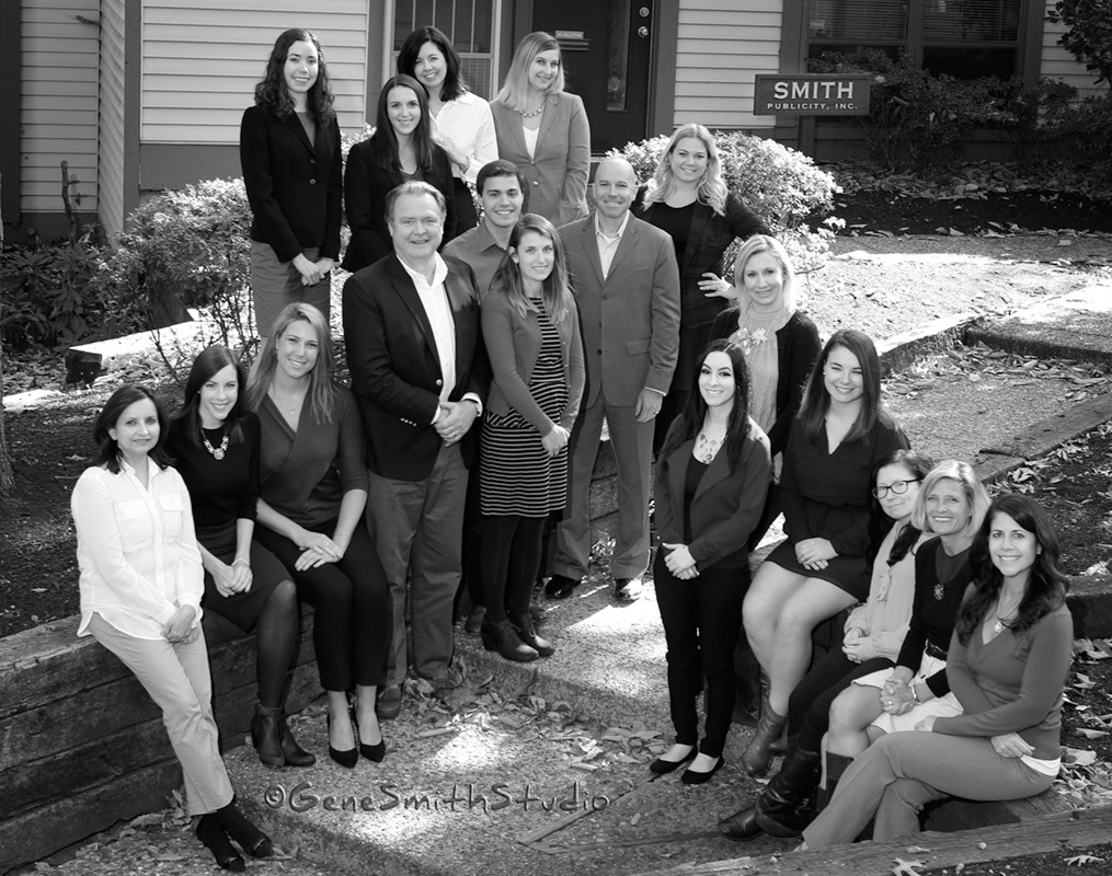 Large group of employees of Smith Publicity pose in front of their headquarters.