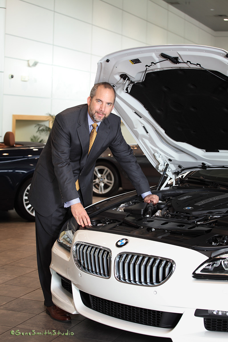 CEO in suit and tie photographed with white BMW in Holman Showroom.
