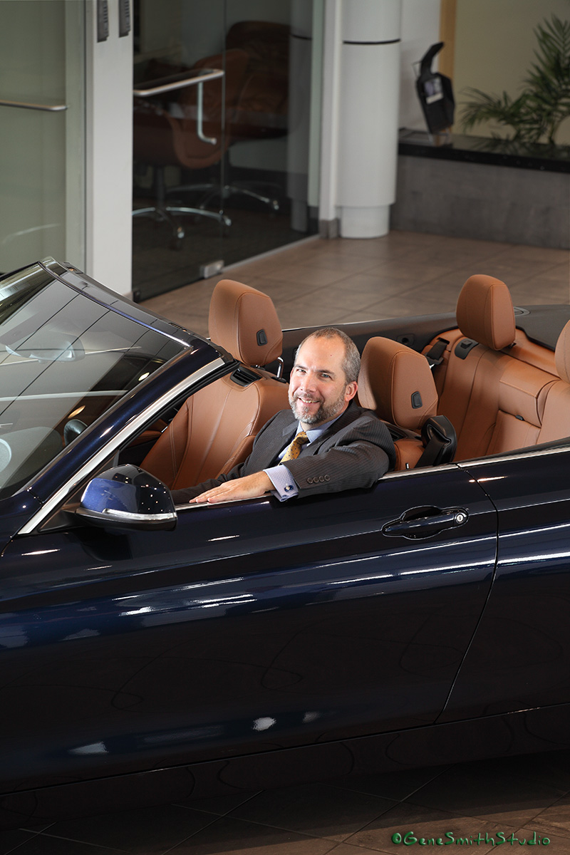 Holman Group CEO Brian Bates in Navy Blue BMW convertible photographed with white BMW in Holman Showroom.