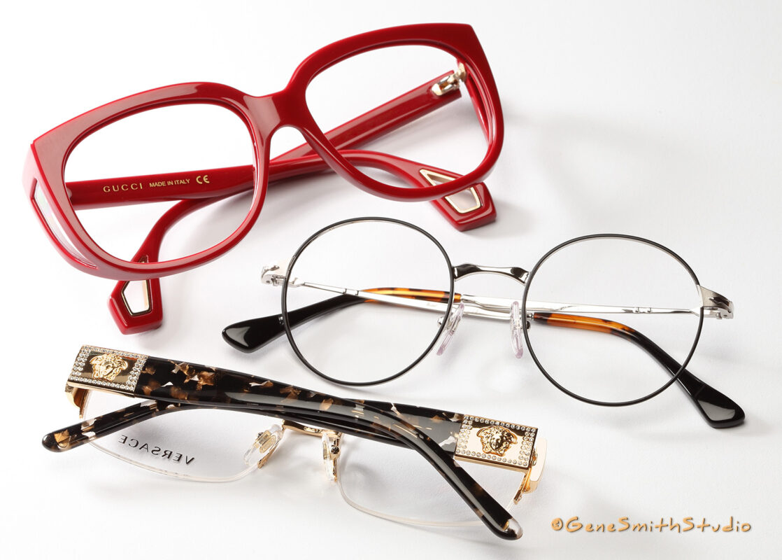 A professional photo for advertising by Gene Smith Studio, Commercial and Headshot Photographer in Cherry Hill, NJ of red GUCCI eyeglasses with luxury gold VERSACE and upscale round lens eyeglass frames.